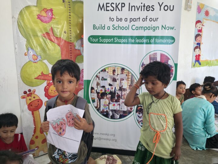 Children with their drawings beside the Build a School banner