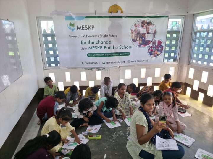Children drawing under the Build a School banner