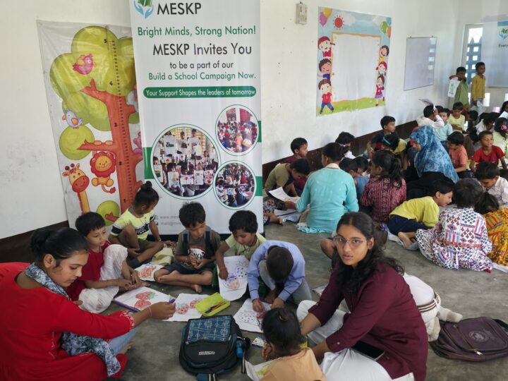 Volunteers and children drawing together at the Build a School day, Kathalia campus