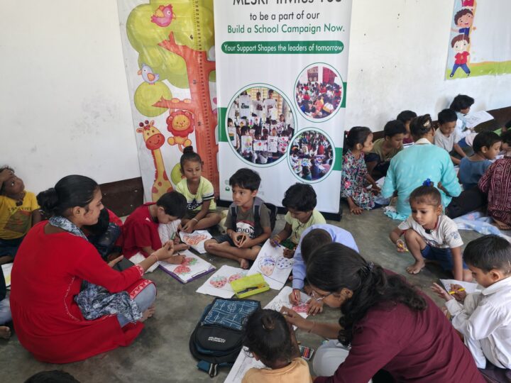 Volunteers helping children draw at the Build a School day