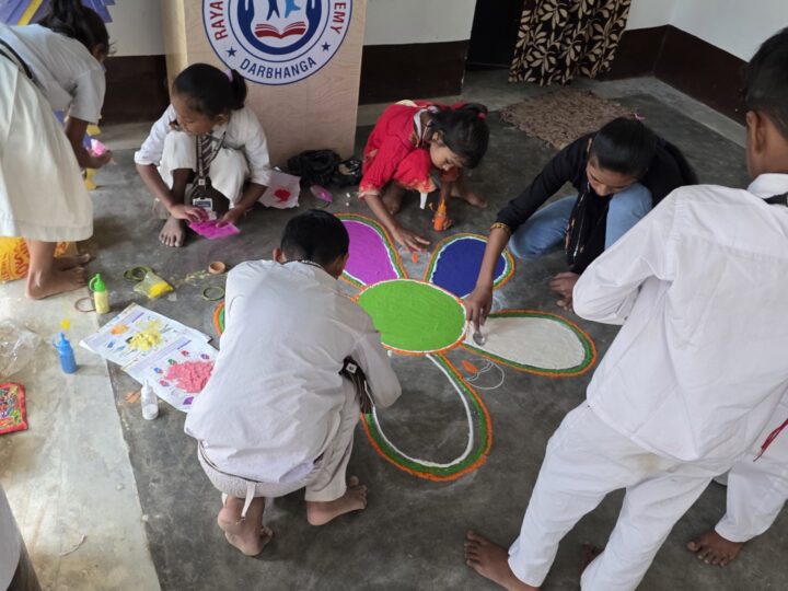 Students colouring a large rangoli
