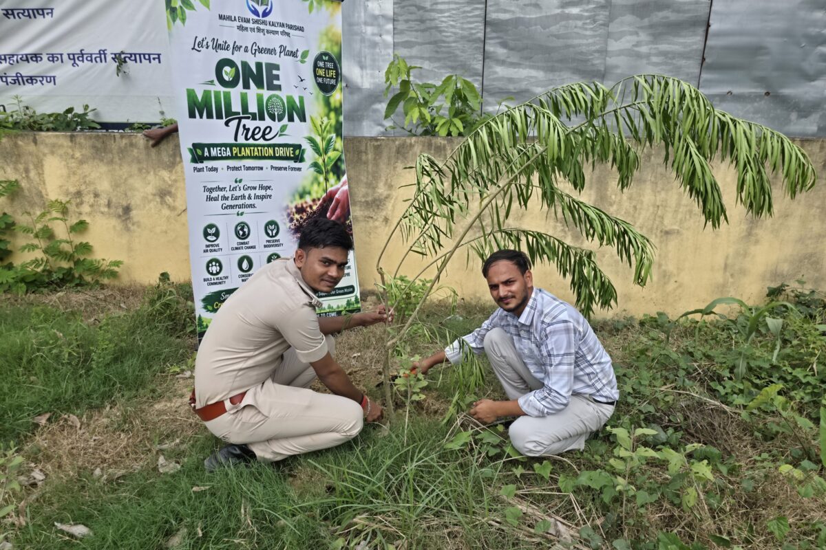 An officer and a volunteer plant a sapling in open ground